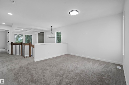 Carpeted open area with recessed lighting, coffered ceiling, and a black wrought iron chandelier - 1737 Crossbill Loop Nw, Edmonton, AB - Indoor Photo Showing Other Room