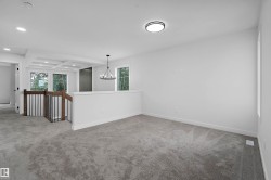 Carpeted open area with recessed lighting, coffered ceiling, and a black wrought iron chandelier - 