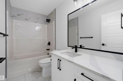 White vanity with black hardware, white countertop, rectangular undermount sink, and black faucet - 