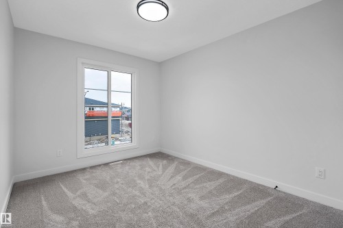 Bright interior space featuring a window, light gray walls, gray carpet flooring, and a flush mount ceiling light - 1737 Crossbill Loop Nw, Edmonton, AB - Indoor Photo Showing Other Room