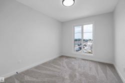 Neutral wall paint, ceiling-mounted light fixture, light grey patterned carpeting, and a window with white trim - 