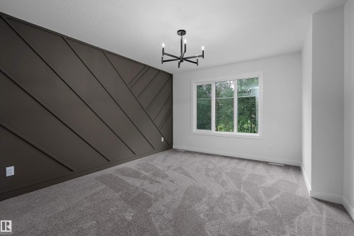 Accent wall with geometric paneling, contemporary chandelier, large picture window, and light gray carpeting - 1737 Crossbill Loop Nw, Edmonton, AB - Indoor Photo Showing Other Room