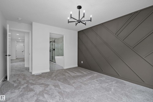 Carpeted room featuring a geometric accent wall and a modern chandelier - 1737 Crossbill Loop Nw, Edmonton, AB - Indoor Photo Showing Other Room
