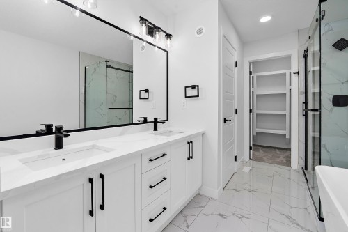 Primary bathroom featuring a dual-sink vanity with white cabinetry, matte black hardware, and a quartz countertop - 1737 Crossbill Loop Nw, Edmonton, AB - Indoor Photo Showing Bathroom
