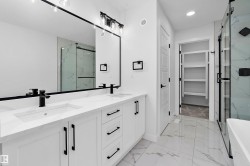 Primary bathroom featuring a dual-sink vanity with white cabinetry, matte black hardware, and a quartz countertop - 