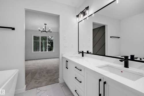 Dual vanity with white cabinetry and integrated sinks, matte black faucets, and a large framed mirror - 1737 Crossbill Loop Nw, Edmonton, AB - Indoor Photo Showing Bathroom