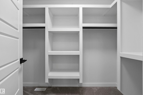Custom built-in shelving and cabinetry featuring white painted finishes, adjustable shelves with dark metal hardware accents, and abundant storage throughout - 1737 Crossbill Loop Nw, Edmonton, AB - Indoor With Storage
