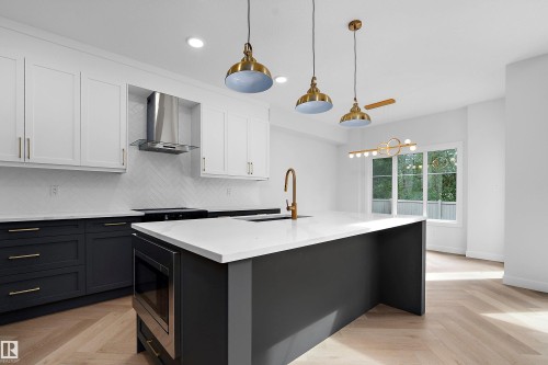 Modern kitchen featuring a large central island with an integrated microwave, white countertops, and a herringbone-patterned wood-finish floor - 1737 Crossbill Loop Nw, Edmonton, AB - Indoor Photo Showing Kitchen With Upgraded Kitchen