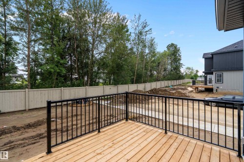 Wood-finish deck with black metal railings, leading to a landscaped yard with a privacy fence - 1737 Crossbill Loop Nw, Edmonton, AB - Outdoor With Deck Patio Veranda