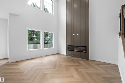 Bright, open living space showcasing herringbone wood-finish flooring, floor-to-ceiling windows with transom detail, and a striking dark vertical wood accent wall anchoring a linear fireplace insert - 1737 Crossbill Loop Nw, Edmonton, AB - Indoor With Fireplace