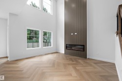 Bright, open living space showcasing herringbone wood-finish flooring, floor-to-ceiling windows with transom detail, and a striking dark vertical wood accent wall anchoring a linear fireplace insert - 
