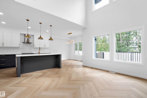 Open-concept living area featuring herringbone wood-finish flooring, a two-story ceiling, and extensive windows - 1737 Crossbill Loop Nw, Edmonton, AB - Indoor Photo Showing Kitchen With Upgraded Kitchen
