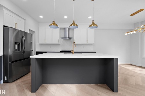 Kitchen featuring a central island with a white countertop, stainless steel appliances, white cabinetry, herringbone wood-finish flooring, and pendant lighting - 1737 Crossbill Loop Nw, Edmonton, AB - Indoor Photo Showing Kitchen With Upgraded Kitchen