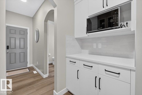 White cabinetry with black hardware, white countertops, and a subway tile backsplash - 347 Bluff Cove, Leduc, AB - Indoor