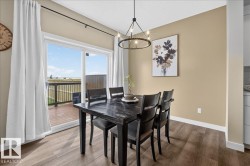 Dining area featuring wood-finish flooring and a contemporary chandelier - 