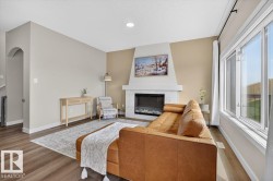 Living area featuring a gas fireplace with a light-toned surround and hearth, recessed lighting, wood-finish flooring, and expansive windows - 
