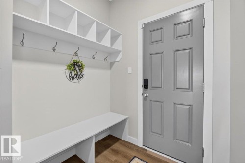 Entryway mudroom featuring white built-in shelving, integrated bench seating, wall-mounted hooks, and wood-finish flooring - 347 Bluff Cove, Leduc, AB - Indoor