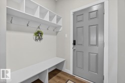 Entryway mudroom featuring white built-in shelving, integrated bench seating, wall-mounted hooks, and wood-finish flooring - 
