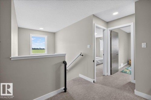 Upper-level landing featuring textured carpet flooring, recessed lighting, and a white framed window - 347 Bluff Cove, Leduc, AB - Indoor Photo Showing Other Room