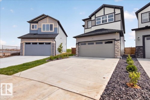 Contemporary exterior showcasing a two-car garage, stone accents, and varied siding - 347 Bluff Cove, Leduc, AB - Outdoor With Facade