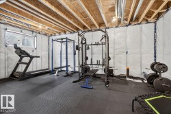 Unfinished basement with exposed ceiling joists and ceiling-mounted lighting - 