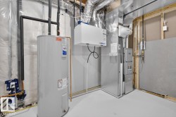Utility room featuring a water heater, furnace, and exposed ductwork - 