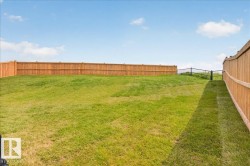 Expansive backyard featuring a manicured lawn, a full wooden privacy fence, and an additional black metal fence - 
