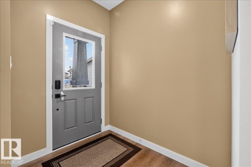 Entryway featuring a paneled door with a clear glass insert, contemporary black hardware, and wood-finish flooring - 347 Bluff Cove, Leduc, AB - Indoor Photo Showing Other Room
