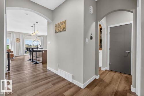 Foyer featuring arched doorways, wood-finish flooring, and a modern paneled door - 347 Bluff Cove, Leduc, AB - Indoor Photo Showing Other Room