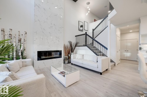 Vaulted living area featuring a tall fireplace with a linear insert and light-toned tile surround - 1776 Crossbill Loop Nw, Edmonton, AB - Indoor Photo Showing Living Room With Fireplace