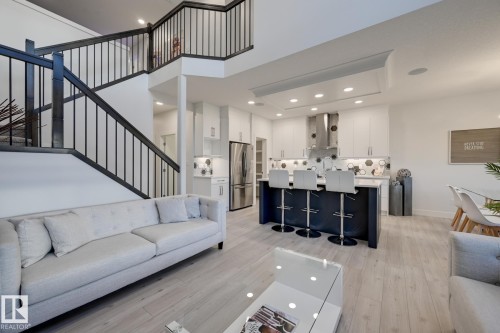 Open-concept living space with a contemporary staircase featuring dark wood and black metal balusters - 1776 Crossbill Loop Nw, Edmonton, AB - Indoor Photo Showing Living Room