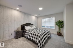 Bedroom featuring a distressed wood-paneled accent wall, recessed lighting, and built-in ceiling speakers - 