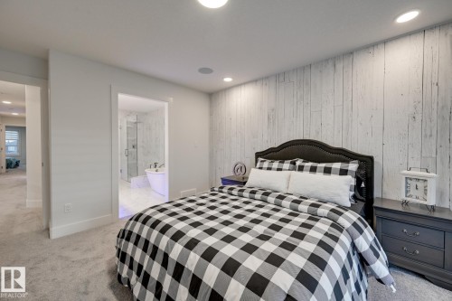 Bedroom featuring a distressed wood-look accent wall, recessed lighting, and light grey carpeting - 1776 Crossbill Loop Nw, Edmonton, AB - Indoor Photo Showing Bedroom