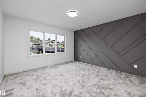 Accent wall with geometric paneling, multiple pane window, plush gray carpeting, and flush mount ceiling light - 1776 Crossbill Loop Nw, Edmonton, AB 
