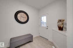 Entryway featuring a solid white door with an integrated window pane, modern hardware, and light wood-finish flooring - 