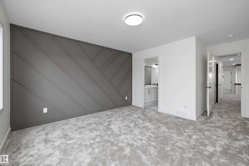 Spacious primary bedroom featuring a striking diagonal shiplap accent wall in charcoal gray, plush carpet flooring, recessed ceiling lighting, and direct access to an ensuite bathroom with vanity and shower enclosure - 1776 Crossbill Loop Nw, Edmonton, AB 