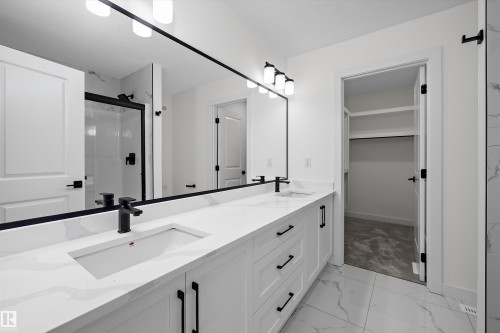 Primary bathroom featuring a dual-sink vanity with white cabinetry, quartz countertop, and matte black hardware - 1776 Crossbill Loop Nw, Edmonton, AB 