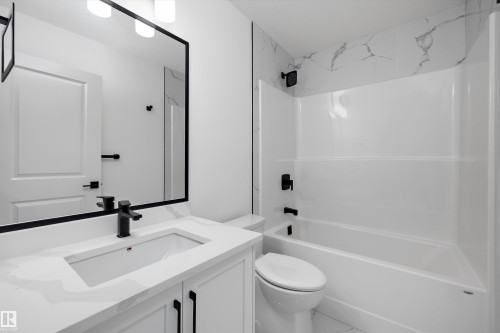 Modern bathroom featuring a floating vanity with rectangular undermount sink, white quartz countertop, and matte black faucet hardware - 1776 Crossbill Loop Nw, Edmonton, AB 