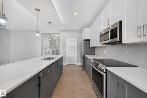 Modern kitchen featuring white upper cabinetry, gray lower cabinetry, and stainless steel appliances - 4620 Alwood Way Sw, Edmonton, AB - Indoor Photo Showing Kitchen With Stainless Steel Kitchen With Double Sink With Upgraded Kitchen