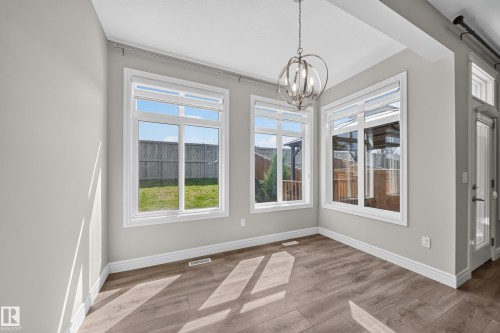 Bright dining area featuring wood-finish flooring, white baseboards, and a contemporary spherical chandelier - 4620 Alwood Way Sw, Edmonton, AB - Indoor Photo Showing Other Room