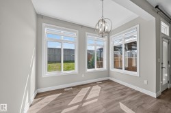 Bright dining area featuring wood-finish flooring, white baseboards, and a contemporary spherical chandelier - 