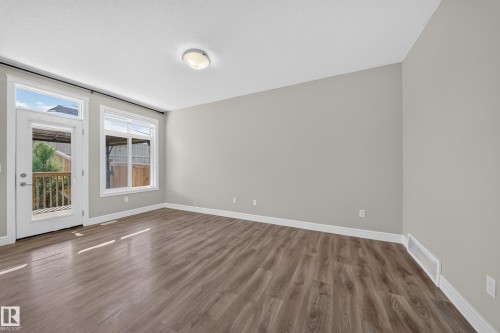 Spacious room featuring wood-finish flooring, light grey walls, white trim, and a contemporary flush-mount ceiling light - 4620 Alwood Way Sw, Edmonton, AB - Indoor Photo Showing Other Room