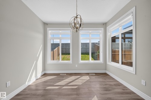 Spacious room featuring wood-finish flooring, light grey walls, and white trim - 4620 Alwood Way Sw, Edmonton, AB - Indoor Photo Showing Other Room