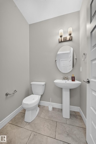 Bathroom featuring a pedestal sink, oval mirror, and tile flooring - 4620 Alwood Way Sw, Edmonton, AB - Indoor Photo Showing Bathroom