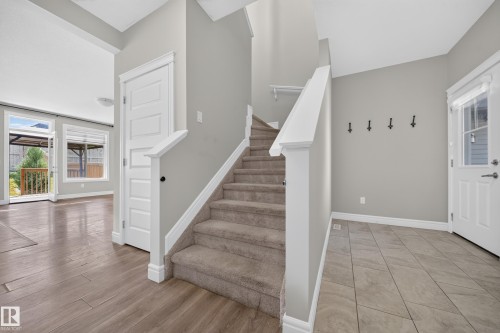 Entry foyer featuring a carpeted staircase with white railings, tile flooring, and a front entry door with a glass insert - 4620 Alwood Way Sw, Edmonton, AB - Indoor Photo Showing Other Room
