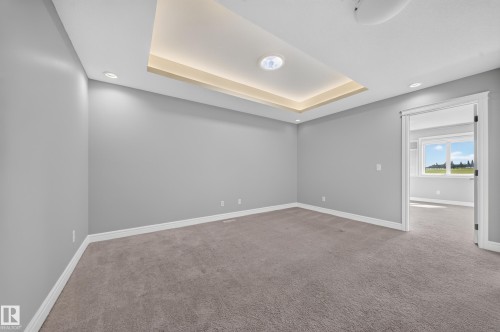 Carpeted room featuring a tray ceiling with recessed lighting, white baseboards, and neutral wall paint - 4620 Alwood Way Sw, Edmonton, AB - Indoor Photo Showing Other Room