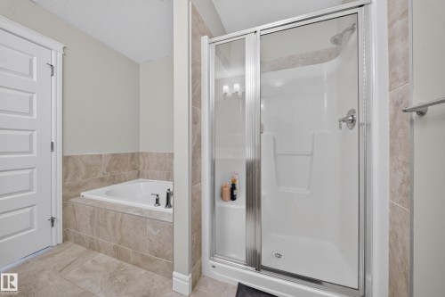 Bathroom featuring a built-in tub with tile surround, a separate shower enclosure with sliding glass doors, chrome fixtures, and complementary tile flooring - 4620 Alwood Way Sw, Edmonton, AB - Indoor Photo Showing Bathroom