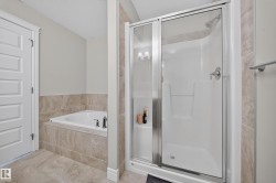 Bathroom featuring a built-in tub with tile surround, a separate shower enclosure with sliding glass doors, chrome fixtures, and complementary tile flooring - 