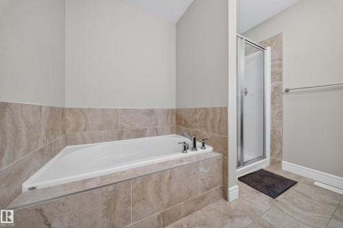 Alcove bathtub with deck-mounted chrome fixtures, complemented by a separate glass-enclosed shower stall - 4620 Alwood Way Sw, Edmonton, AB - Indoor Photo Showing Bathroom