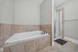 Alcove bathtub with deck-mounted chrome fixtures, complemented by a separate glass-enclosed shower stall - 